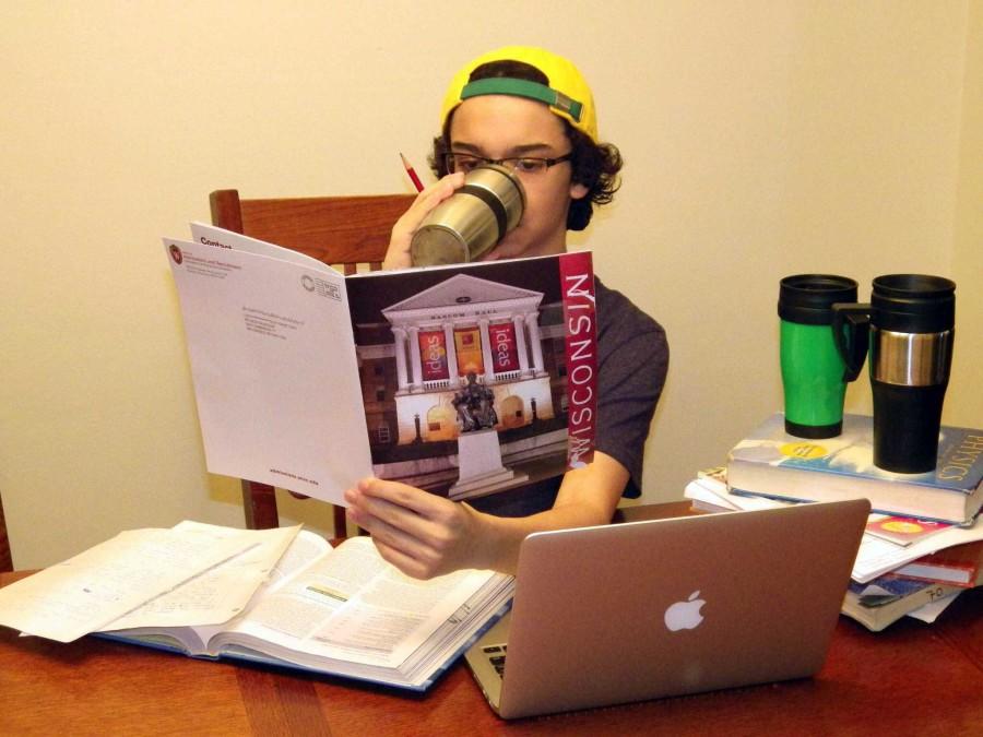 Ricardo Matias (‘15) peruses a UW-Madison pamphlet while working on his Common Application and various homework assignments from school. If the three coffee mugs are any indication, it is going to be a long night for him.