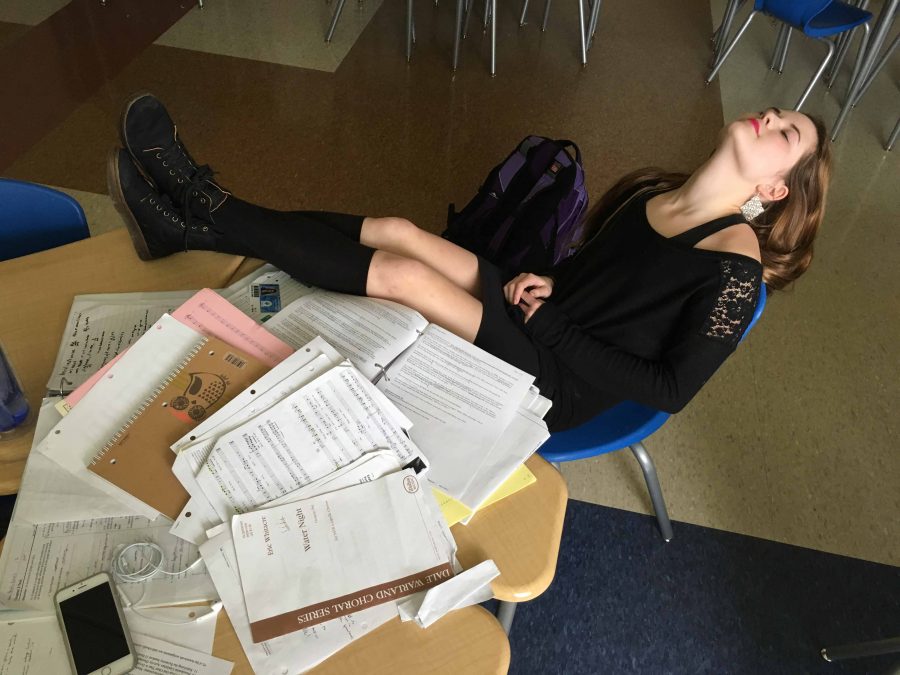Senior Arcadia Schmid shows her apathy for school with her head back, feet up, and eyes shut. Undone AP Microeconomics homework,  crisp choir music, and untouched binders are strewn across the desk. Her serious case of senioritis can only be cured by graduation. 