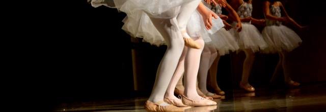 Ballerinas gracefully line up on stage in position to dance into the next move.