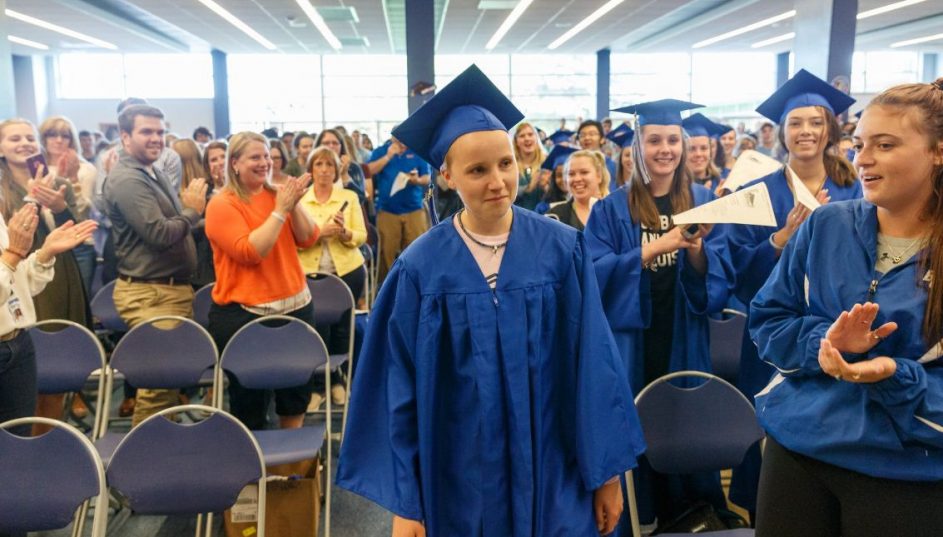 Andrew Wernicke approaches the stage in his cap and gown amidst a standing ovation from his classmates, BC staff, and community members.