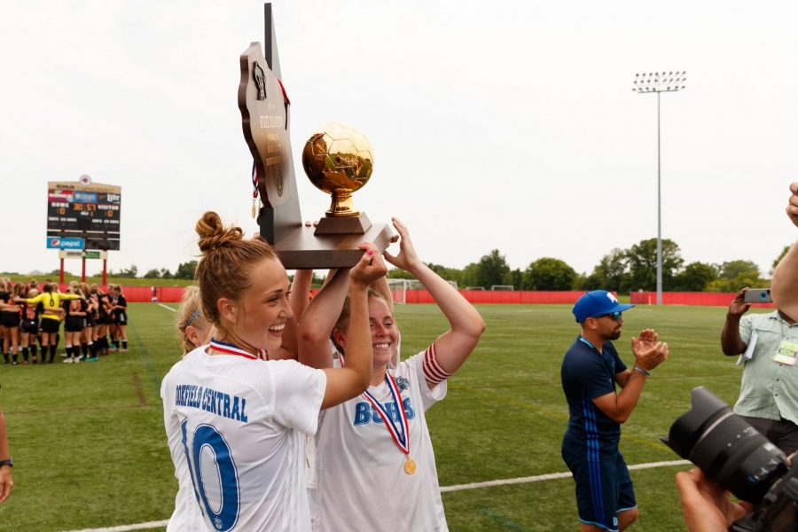Former captains Brandi Thomsen and Emma Staszkiewicz hold up the state champion trophy and celebrate their victory. 