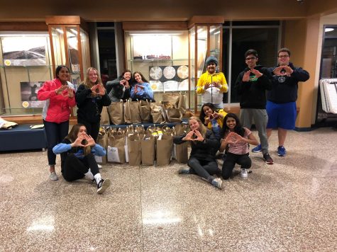 DECA members throw up the DECA diamond after a successful round of collection. All the bags pictured and the ones gathered by the one group that had not
returned in time for the photo were delivered to the Waukesha Food Pantry the
next day.
Back row: Iksha Dhawan (‘20), Emily Berger (‘20), Mikayla Utnemer
(‘20), Rawan Hamadeh (‘20), Harshman Sihra (‘22), Rajat Mittal (‘19), and Brad
Steinert (‘19). 

Front row: Lauren Roskopf (‘20), Maggie Conlon (‘20), Veda Menon (‘22), and Janani Sundar (‘19). (Photo from the 2018 Trick-or-Can).